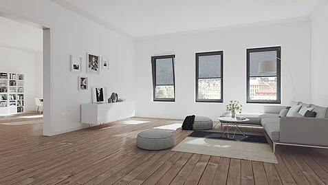Helles, modernes Wohnzimmer mit Holzfußboden, grauem Sofa, Teppich, niedrigen Tischen und drei Fenstern.