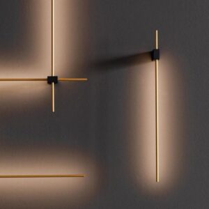 Moderne Wandlampen mit dünnen, goldfarbenen Leuchtstäben an dunkler Wand.